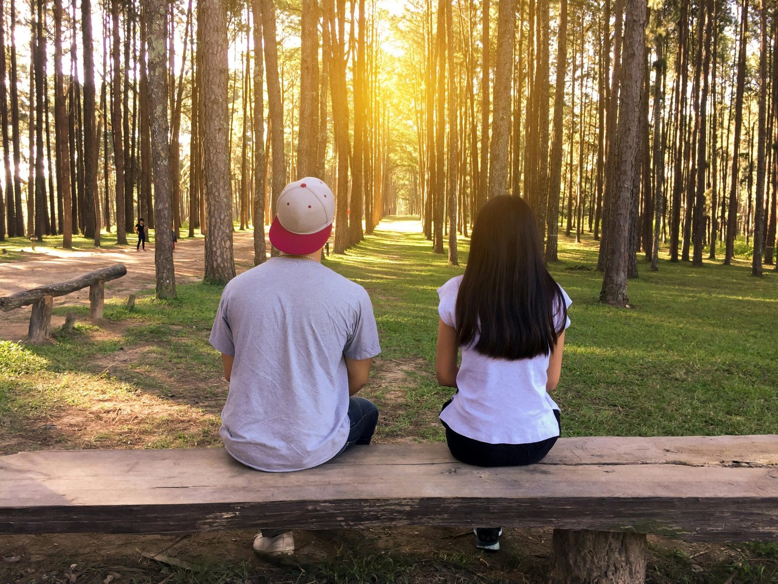 Couple sitting on bench in forest park during sunset – Duo Desire moment.