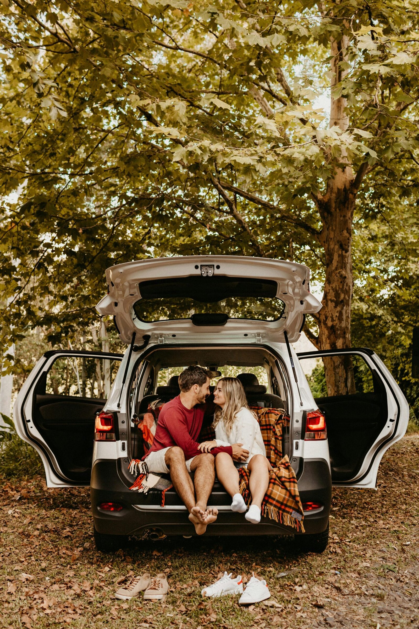 Couple cuddling in car trunk surrounded by trees — Duo Desire love vibes.