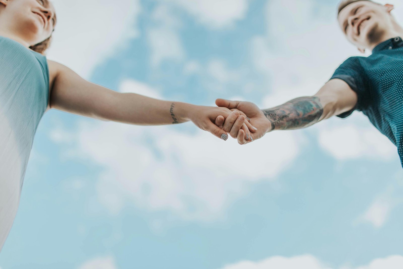 Couple holding hands against a bright sky, symbolizing love, from Duo Desire.